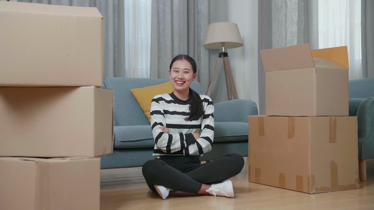 Woman Sitting Among Moving Boxes in a Living Room