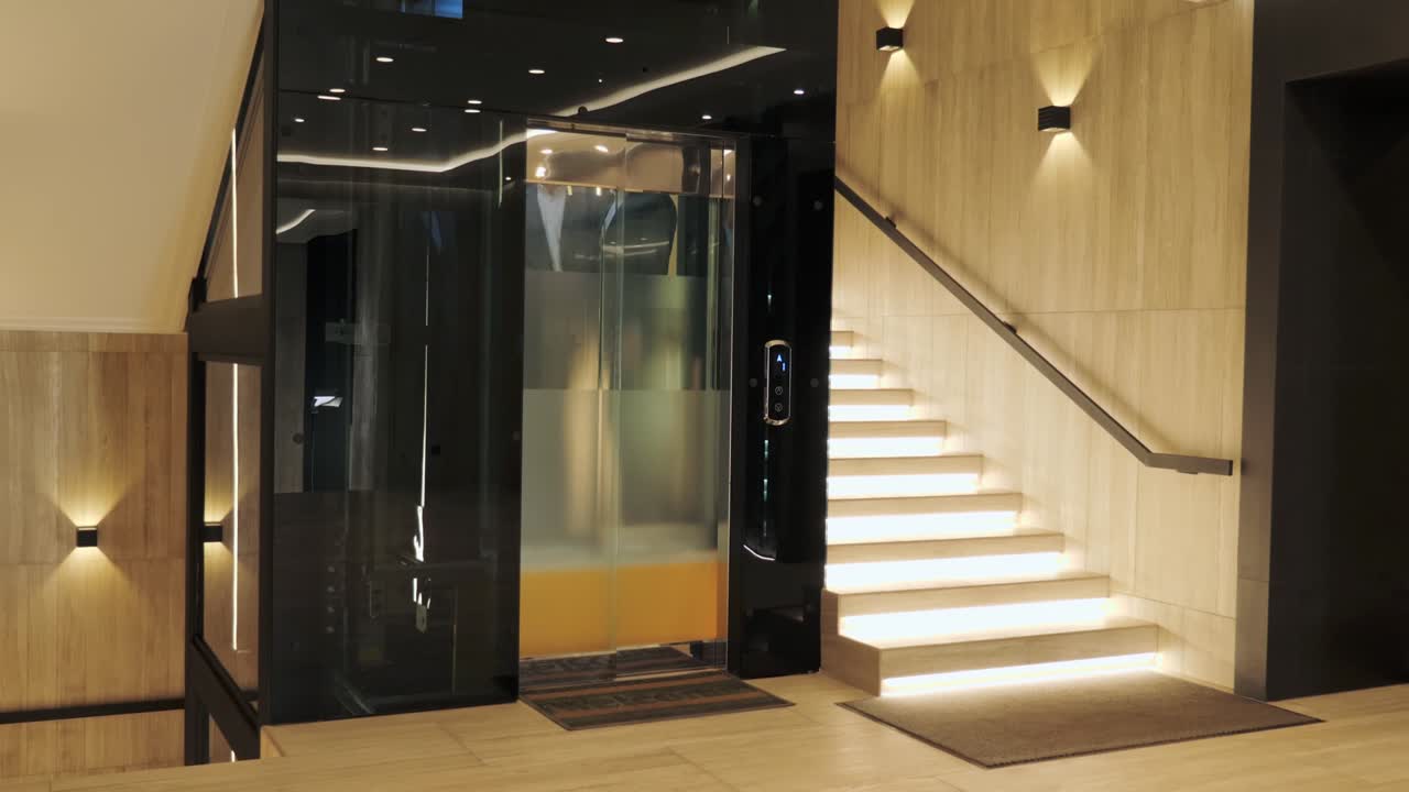 Group of businessmen are moving up in a modern glass elevator. Successful people take the lift to the top of Business Center. Stylish man and woman talking discuss the project inside lift.
