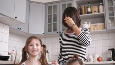 madre y dos hijas están bailando en la cocina