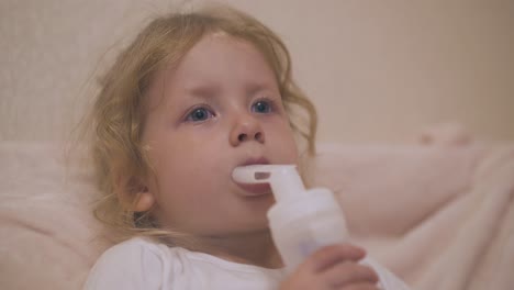 cute girl breathes with inhaler to cure bronchitis in bed