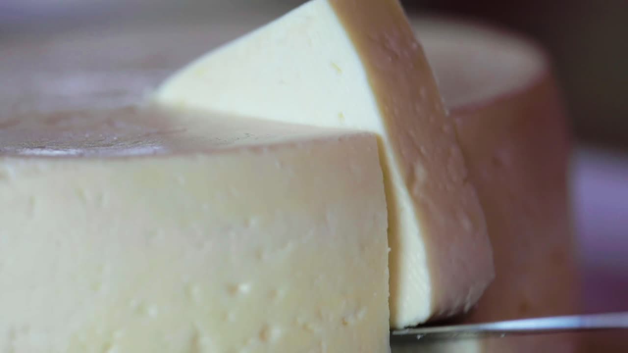 el cuchillo corta y toma una rebanada de la gran rueda de queso, toma de primer plano