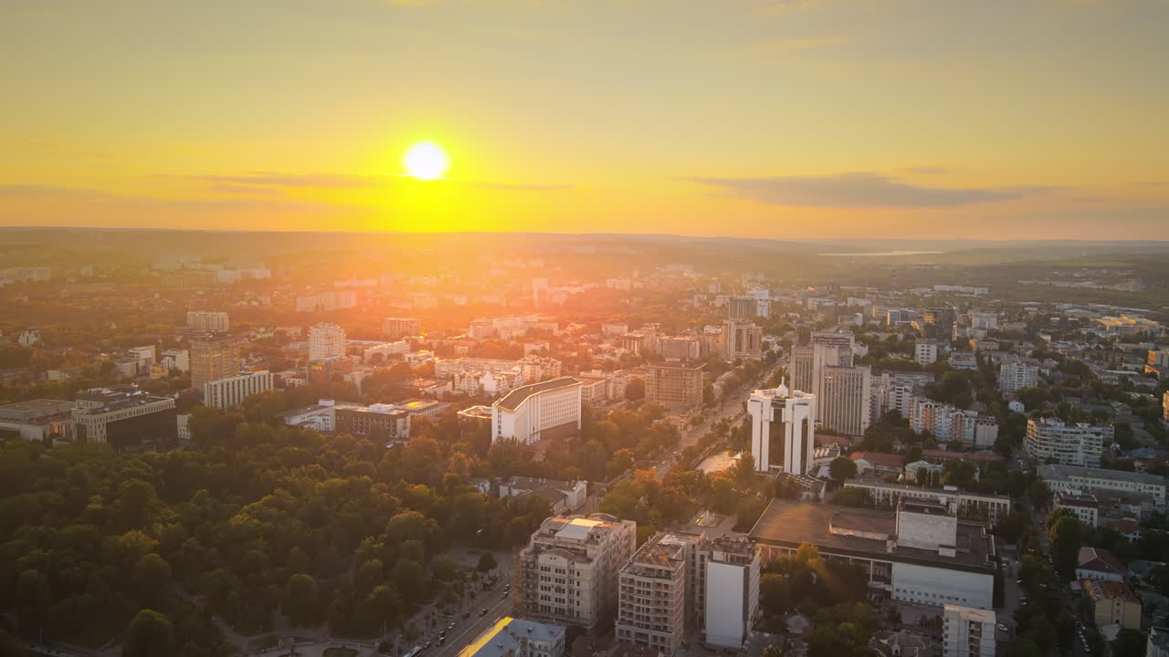 Vista aérea de drone do centro de Chisinau ao pôr do sol. Vista panorâmica de vários edifícios, Parlamento, Presidência, estradas com carros em movimento e árvores exuberantes. Moldávia