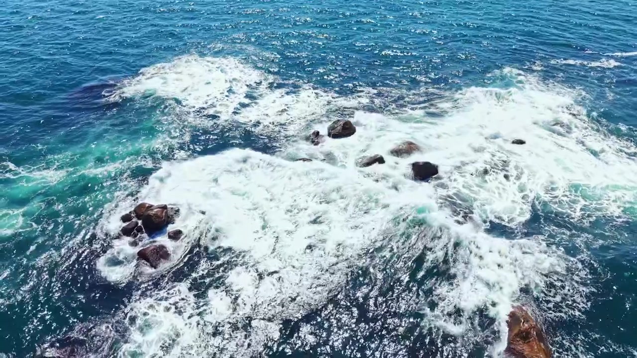 Onde si infrangono sulle rocce nell'oceano durante una giornata di sole vicino alla riva
