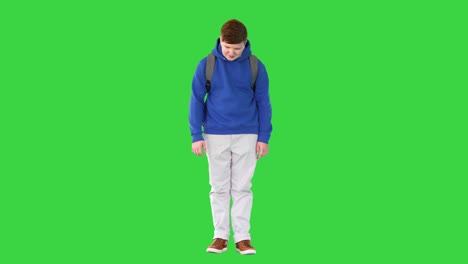 young student with backpack standing on a green screen, chroma key