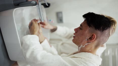 Gay-couple-in-bathroom-in-the-morning,-washing-face-in-front-of-mirror