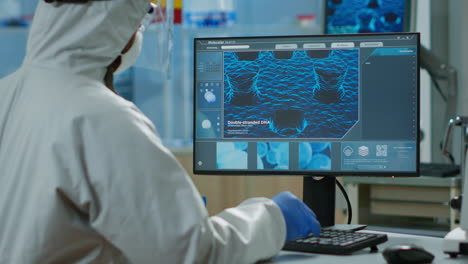 back view of chemist man in coverall typing on computer analysing vaccine evolution