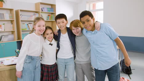 multiethnic students group hugging and looking at camera in english classroom