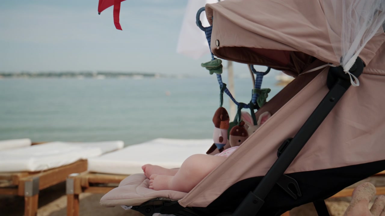 Scène de plage estivale paisible avec un bébé se reposant dans une poussette près d'une mer calme et de transats de plage