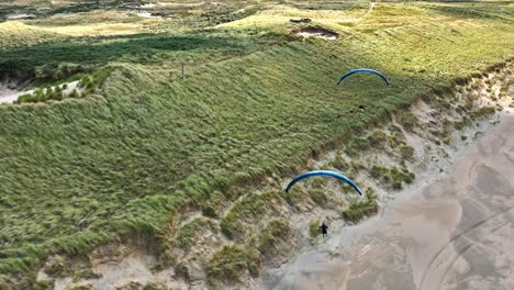 emocionante duna volando por dos parapentes a lo largo de la costa de langevelderslag, avión no tripulado