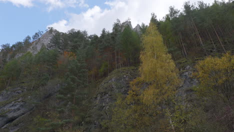 Looking-up-with-lateral-movement,-a-colorful-autumn-mountain-landscape-against-a-blue-sky-with-clouds