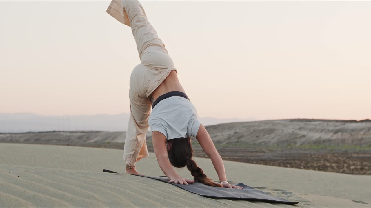joven instructora de yoga morena en una colina de arena realizando una rutina de yoga temprano en la mañana