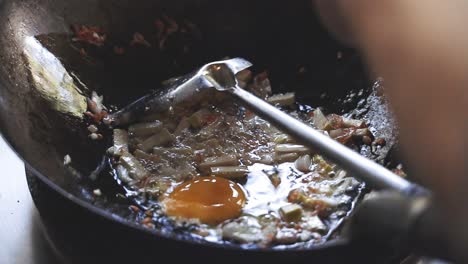 cooking pad thai series: slo mo chef putting in eggs in hot wok at thai street food shop