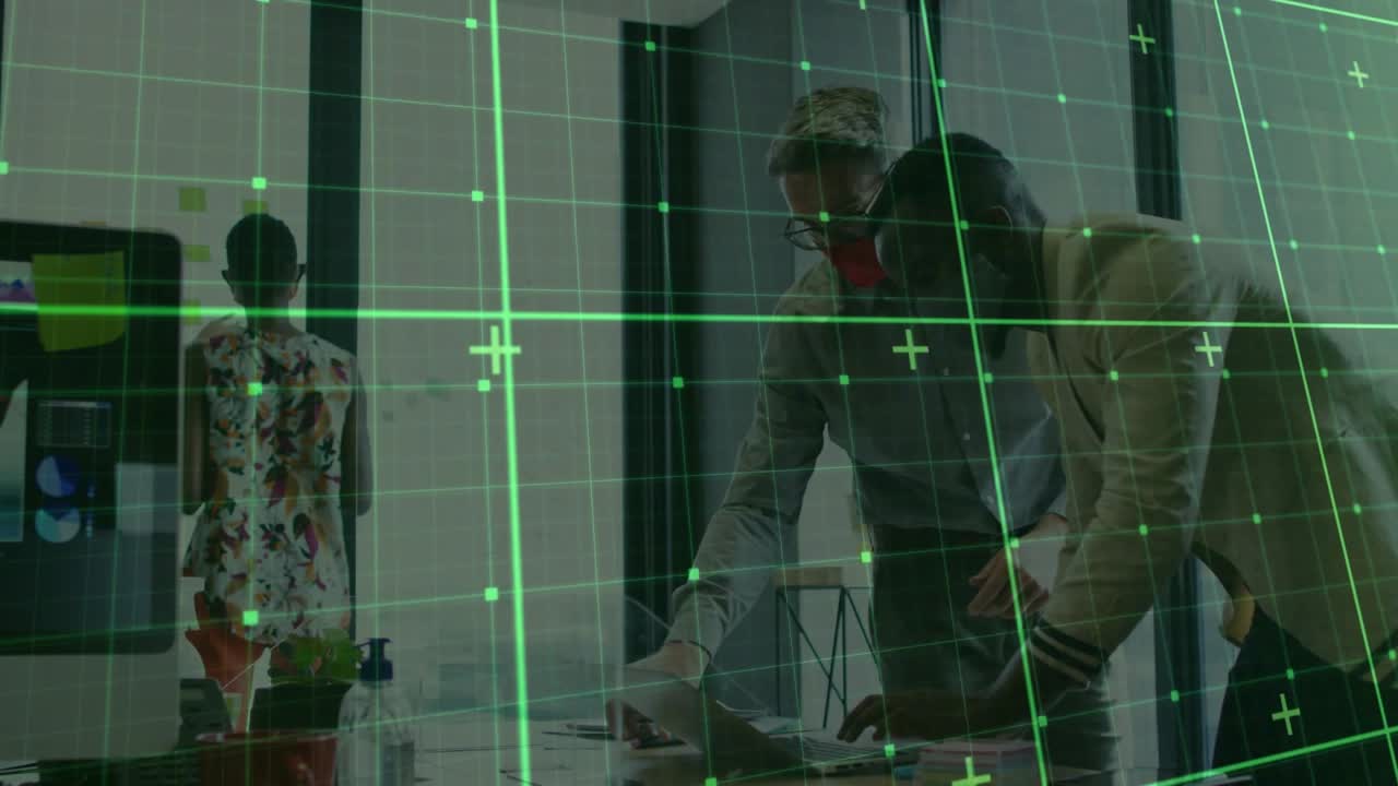 Stående medarbejder tapper på telefon, starter grønt gitter, mens kontorteam gennemgår papirer til planlægning