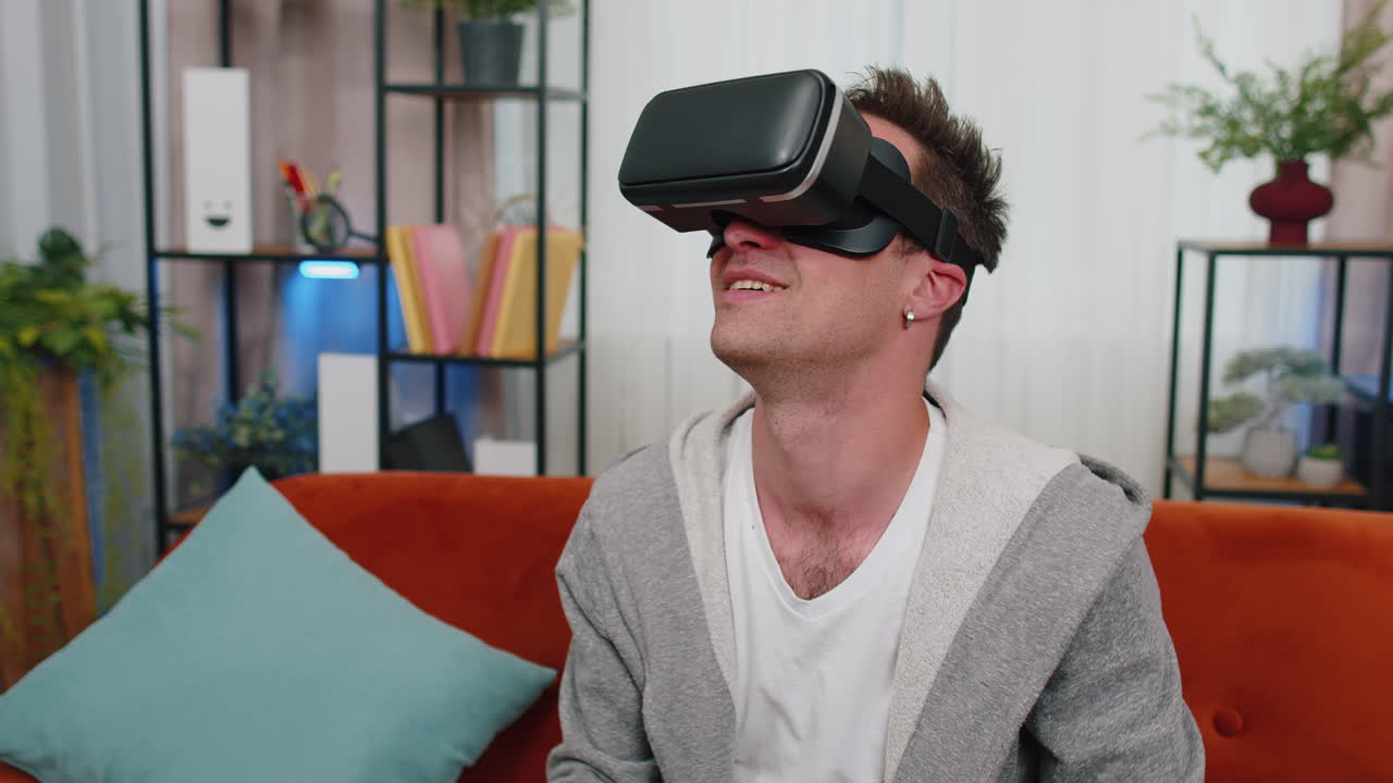 joven usa gafas de realidad virtual en casa juega videojuegos en 3d haciendo gestos con las manos