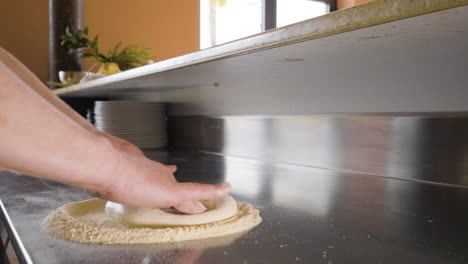 close up view of a chef hands kneading pizza dough on a restaurant kitchen countertop