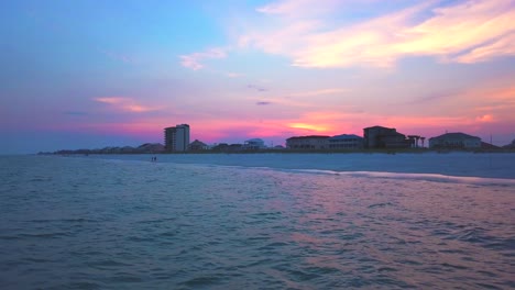 Low-reverse-flying-drone-shot-of-the-ocean-at-sunset