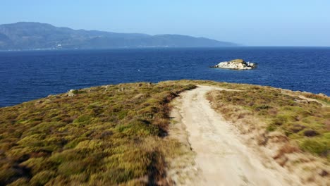 Drone-flies-by-woman-driving-ATV-from-the-edge-of-the-land-next-to-the-sea