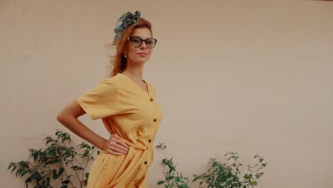 fashionable woman in yellow dress and glasses posing outdoors