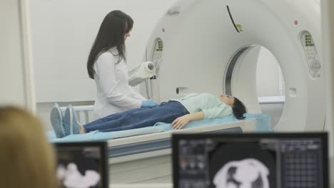 female patient is undergoing ct or mri scan under supervision of a radiologist in modern medical clinic. patient lying on a ct or mri scan bed, moving inside the machine.