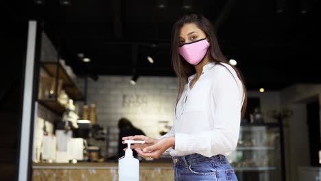 woman washing hands in a cafe with mask on