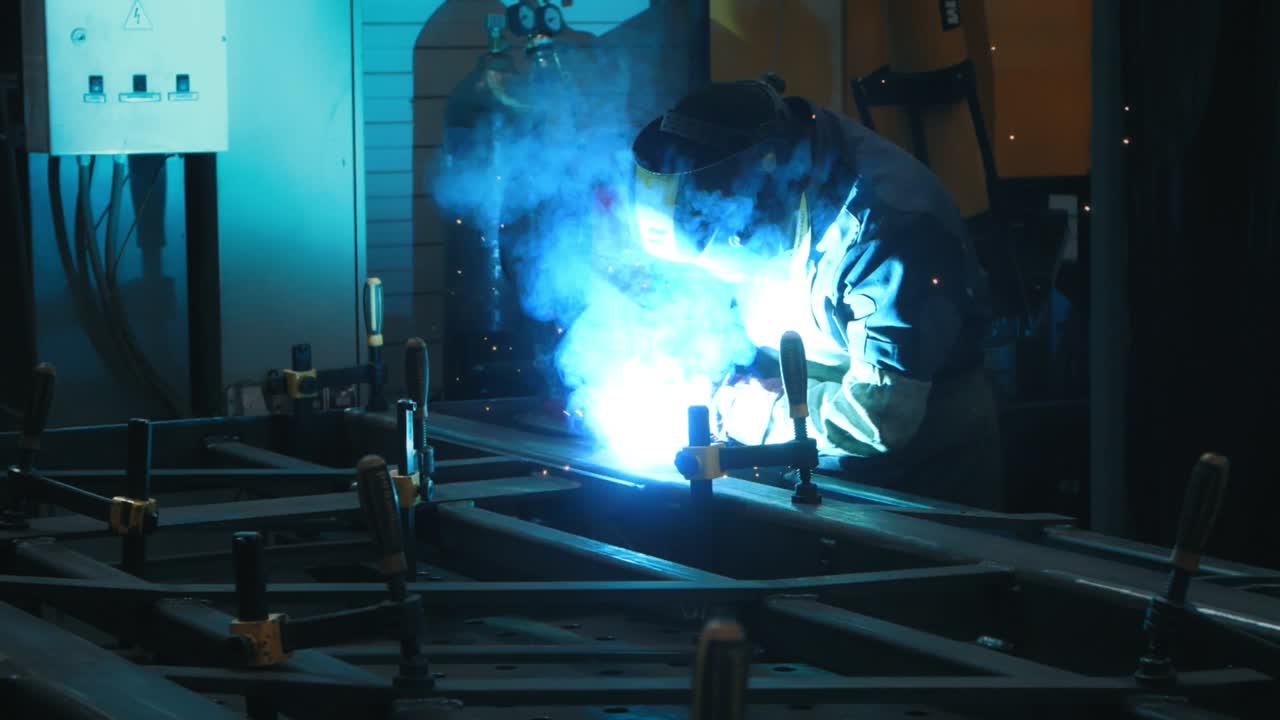 Metal welding process in dark industrial room. Metal steel structure in workshop