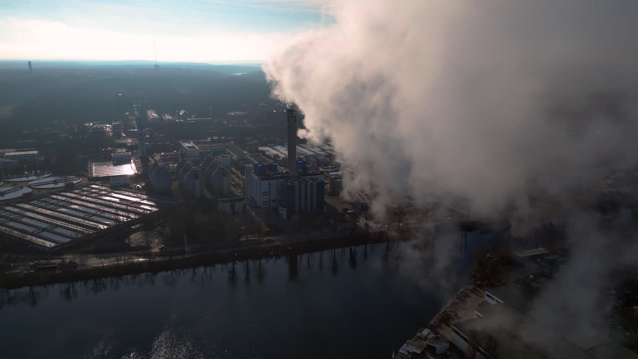 Industrial chimneys emitting white smoke over city skyline under blue sky, concept of pollution. Best aerial view flight panorama overview drone
