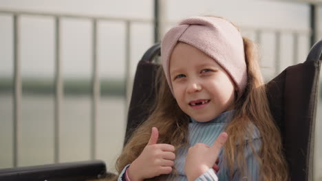 Toothless-girl-turns-to-camera-showing-thumbs-up-gesture