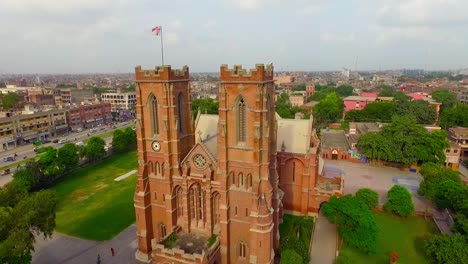 vista aérea de una hermosa iglesia antigua con la ciudad al fondo, hermosos árboles y césped alrededor de la iglesia, palomas volando sobre la iglesia, gente moviéndose fuera de la iglesia