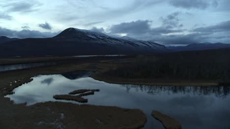 Aerial-drone-dolly-towards-kebnekaise-lappland-sweden,-calm-water-reflecting-sky