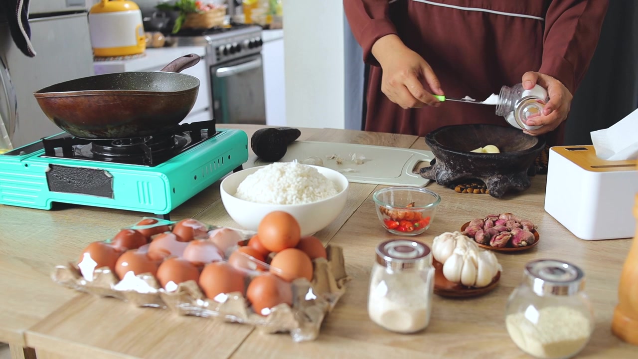 Wanita menyiapkan bahan-bahan segar dan rempah-rempah untuk memasak nasi goreng tradisional di dapur rumah