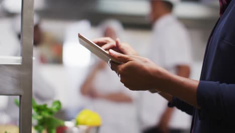 african american female manager using tablet in restaurant kitchen