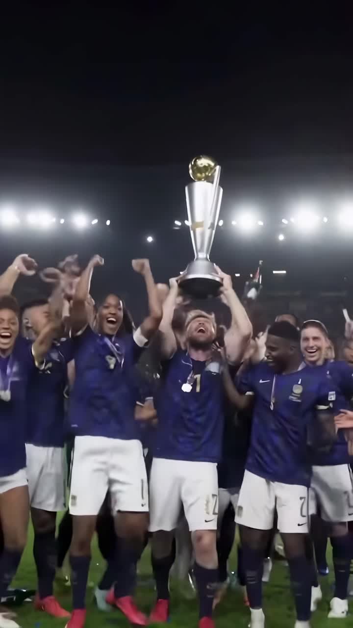 Video ripreso dal basso di una squadra di calcio esultante che solleva un trofeo sotto i riflettori dello stadio.
