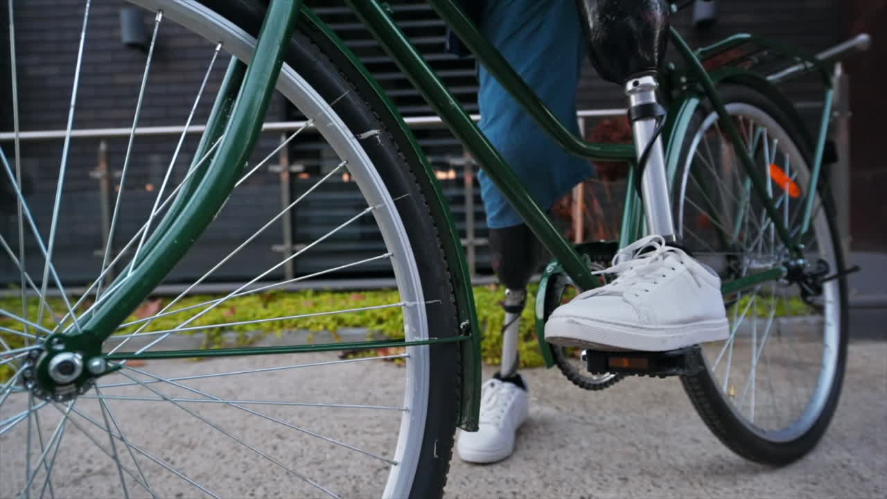 Slow motion view of a man with prosthetic legs. Getting on his bike and driving away