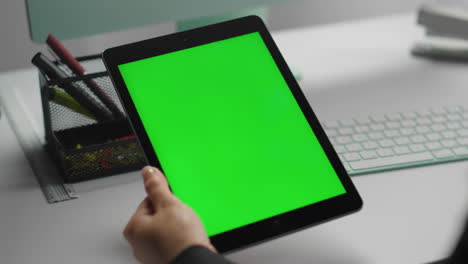 el gerente usando la tableta de maqueta con un primer plano de pantalla verde. las manos sostienen la tecla de croma
