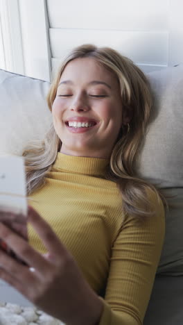 vertical video of happy biracial woman reading book at home, slow motion