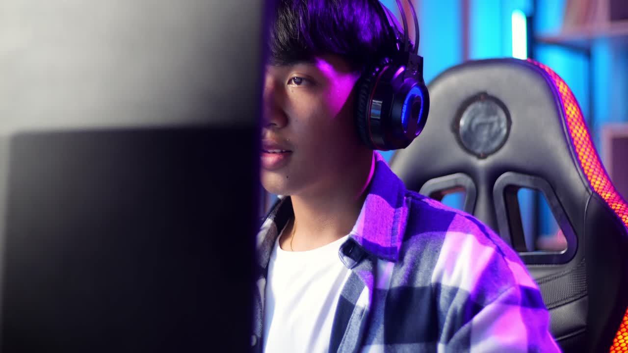 흥분한 아시아 십대 소년 게이머가 컴퓨터에서 비디오 게임을 하면서 승리를 축하합니다.