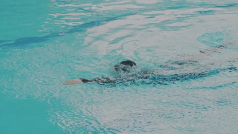 tracking shot of young woman swimmer doing freestyle in swimming pool