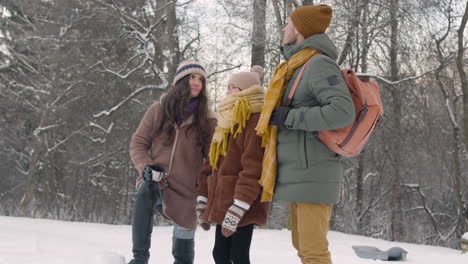 father, mother and daughter talking in a snowy forest