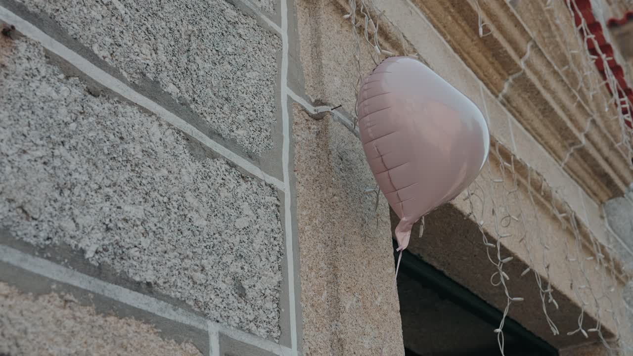 Soft pink heart balloon drifting gently near textured stone