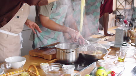 chef cooking pasta with assistance of students during culinary class