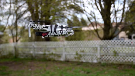 drone camera flying in the wide green area encloses of white fence and surrounded with tall trees and variety of plants - close up shot