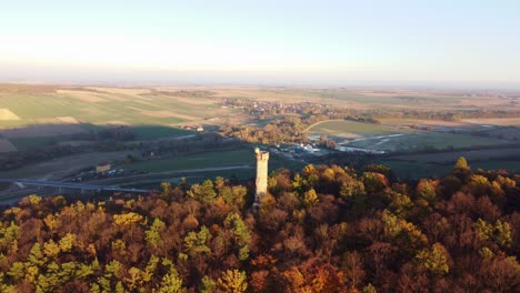 aerial descend to cvilín lookout tower in krnov, czech republic, surrounded by vibrant autumn trees at sunset