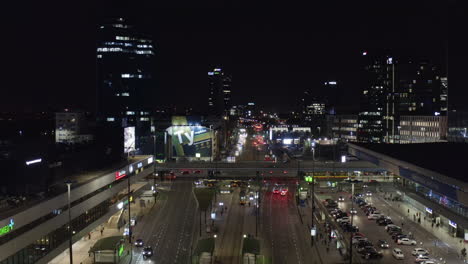 Volar-Hacia-Atrás-Sobre-La-Calle-Ancha-Que-Conduce-Alrededor-Del-Edificio-De-La-Estación-Central-De-Trenes.-Tráfico-Nocturno-En-El-Centro.-Varsovia,-Polonia