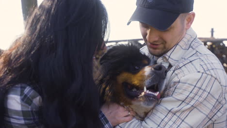 Close-up-view-of-caucasian-couple-squatitng-and-petting-their-dog-in-the-countryside