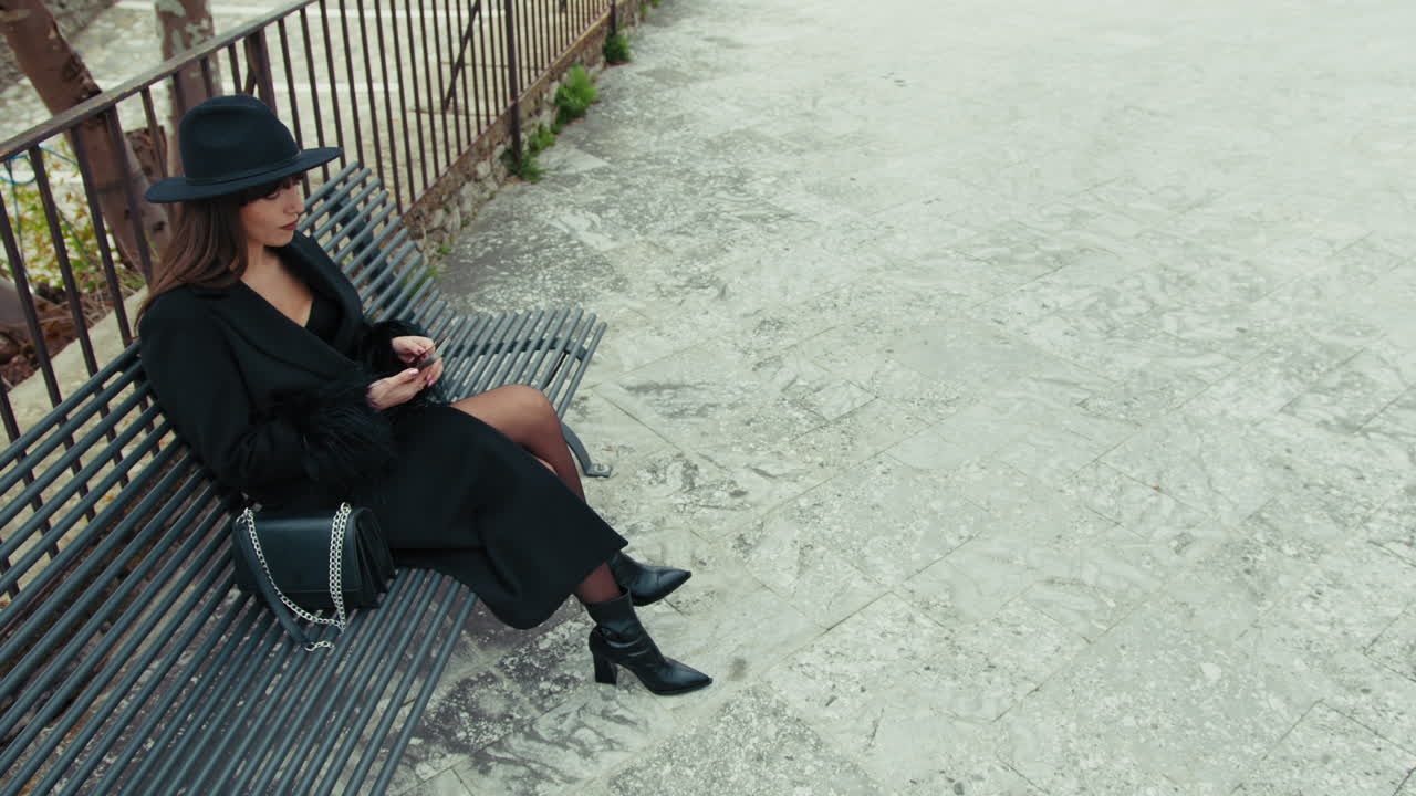 Woman Chatting With The Smartphone Sitting On The Bench In The Square