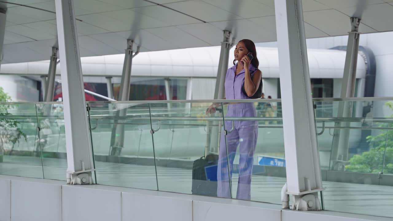 Woman with Luggage Talking on Mobile Phone at Airport