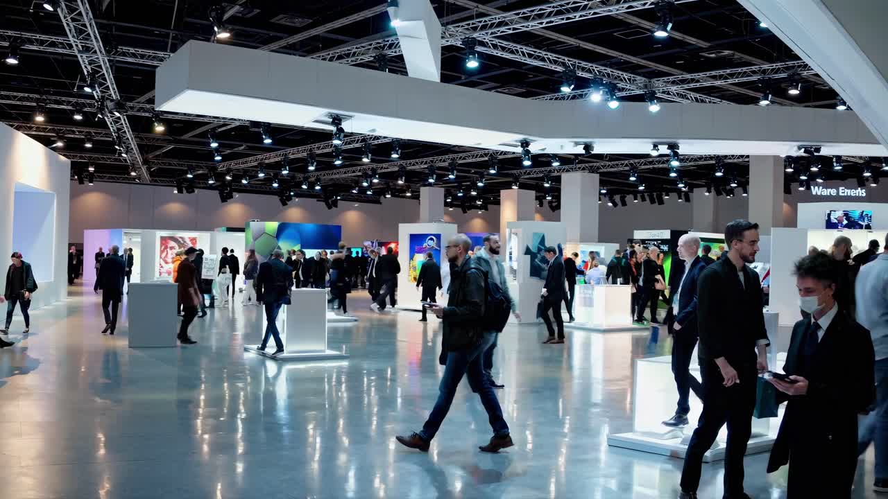 Tomada em grande angular de uma movimentada feira de tecnologia com participantes explorando estandes.