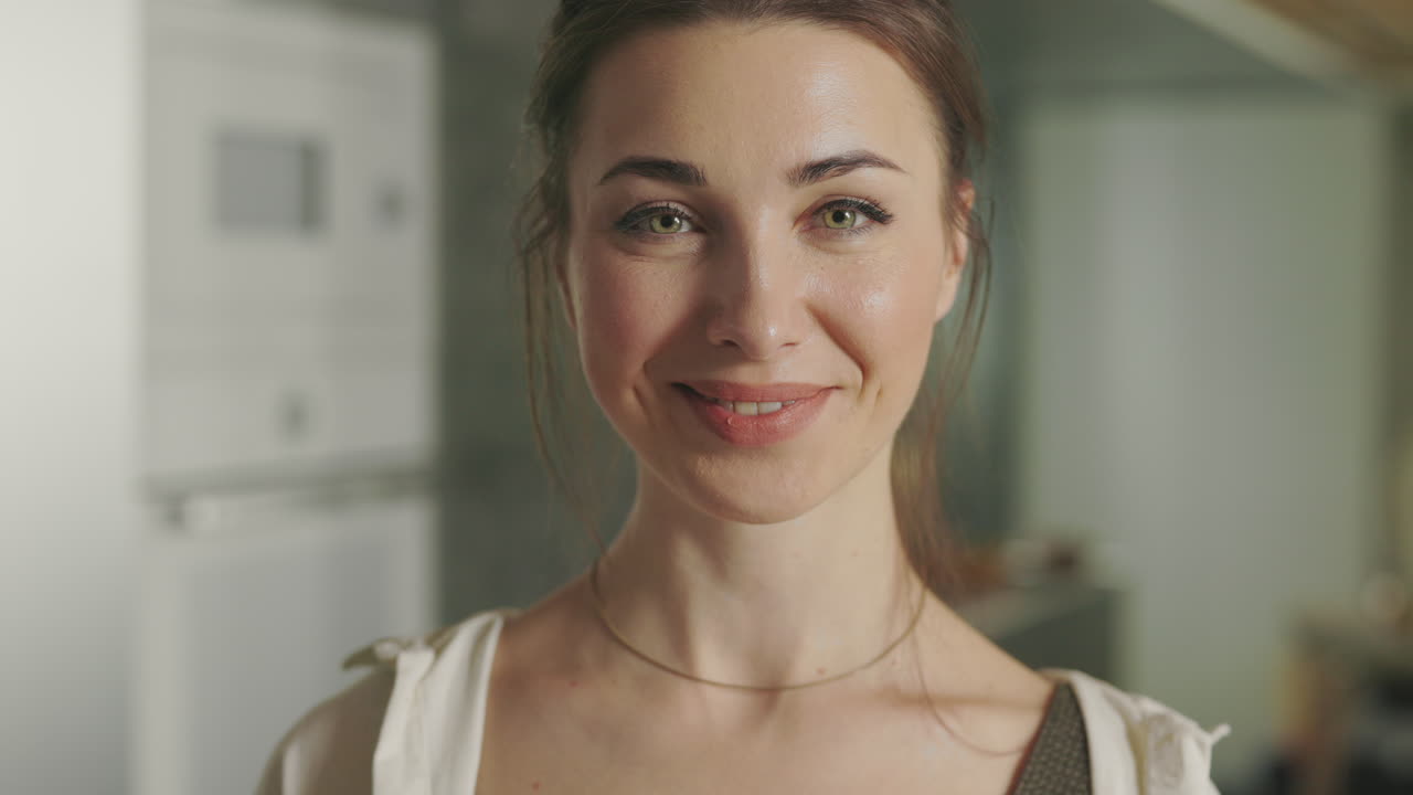Woman playfully holding red apples in a kitchen