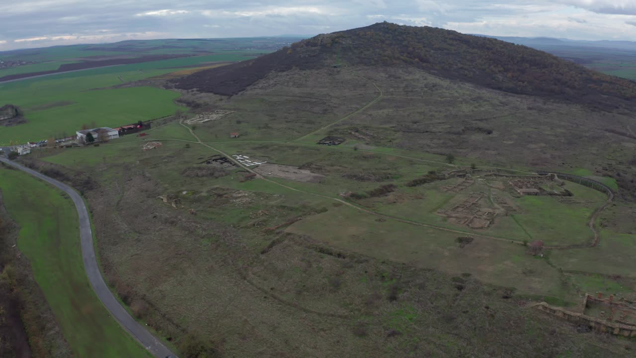 산 정상 의 공중 전망, 흐린 날 에 초록색  ⁇  으로 둘러싸여 있으며, 배경 에 마을 이 있다