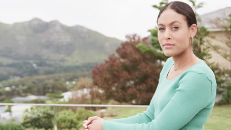 portrait of happy biracial woman standing on balcony at home, copy space, slow motion